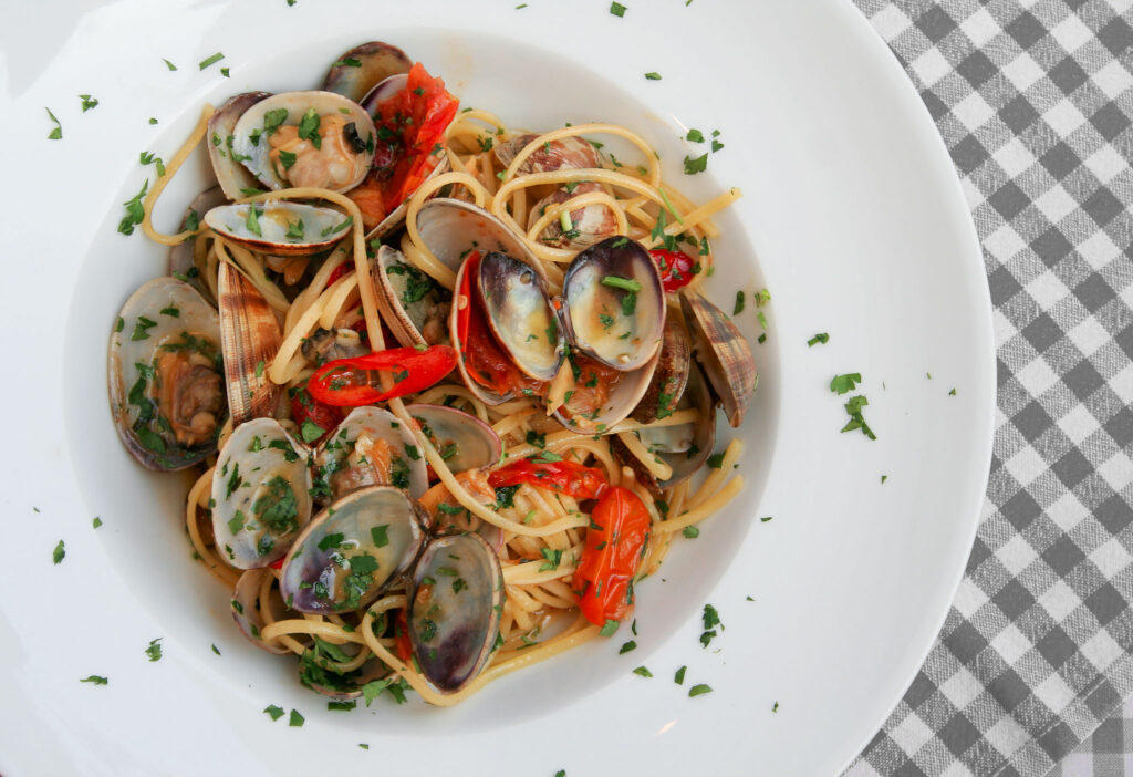 Köstliche Foodfotografie - Ein großer Teller mit Muschel-Pasta und einem Hauch von Chili.