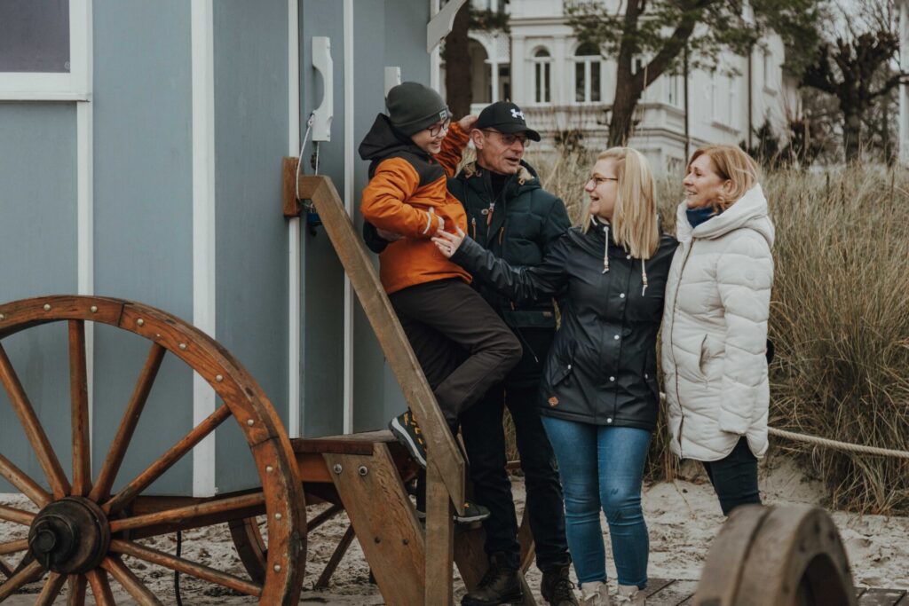 Familienshootings auf Rügen: Oma, Opa, Tochter und Enkel stehen in Winterkleidung, lachend in einer Gruppe vor dem Badekarren in Binz.
