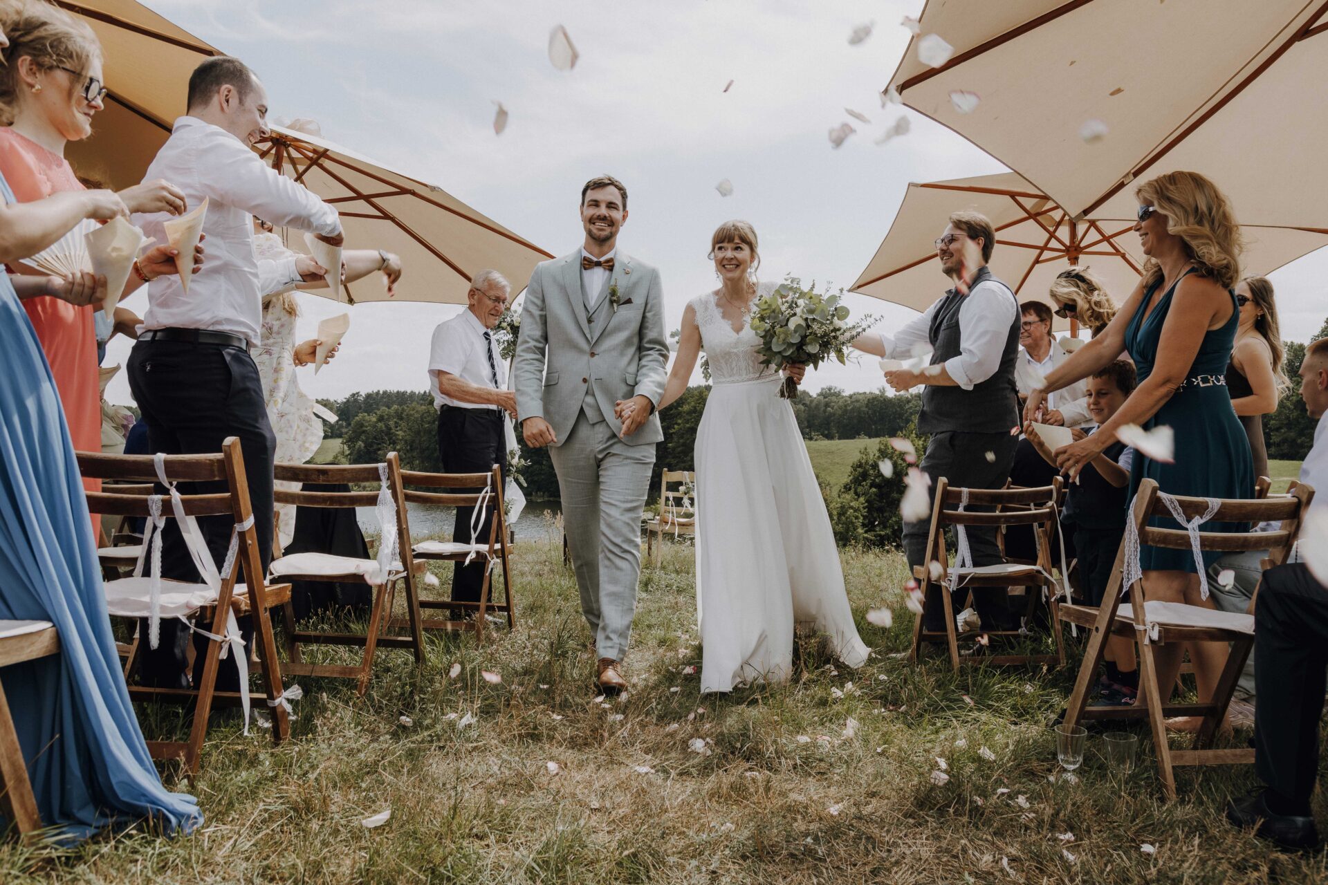 Brautpaar läuft nach der Trauung freudestrahlend durch ein Spalier aus Gästen auf einer sommerlichen Outdoor-Boho-Hochzeit – authentischer Moment voller Emotionen, eingefangen von Hochzeitsfotografin auf Rügen.